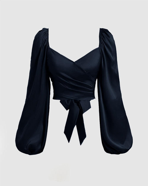 Front view of Black top featuring a front bow, solid color, and lantern sleeves with a braided tie back, pleated in navy blue.