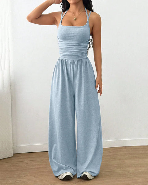 A woman in an ice blue sleeveless wide-leg jumpsuit stands confidently, showcasing a casual yet stylish look.
