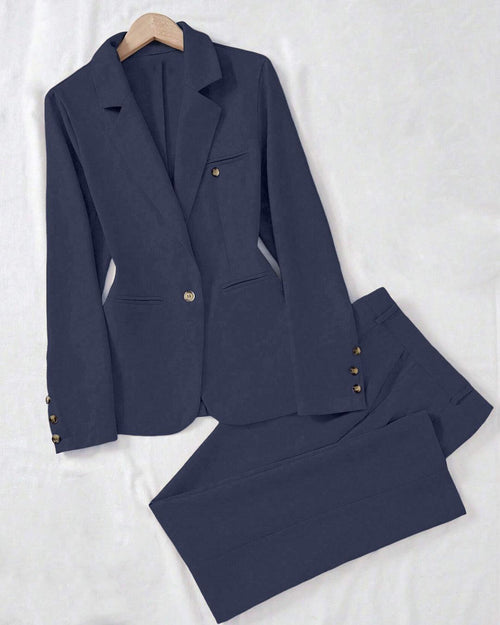 Flat lay of navy blue jacket and pant sets featuring a tailored blazer with button and matching straight-leg trousers on a white background.