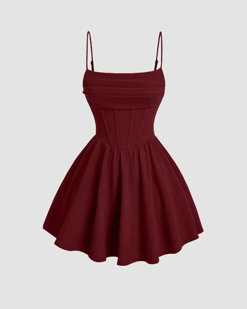 A maroon pleated waist cami short dress featuring straps and a decorative bow.