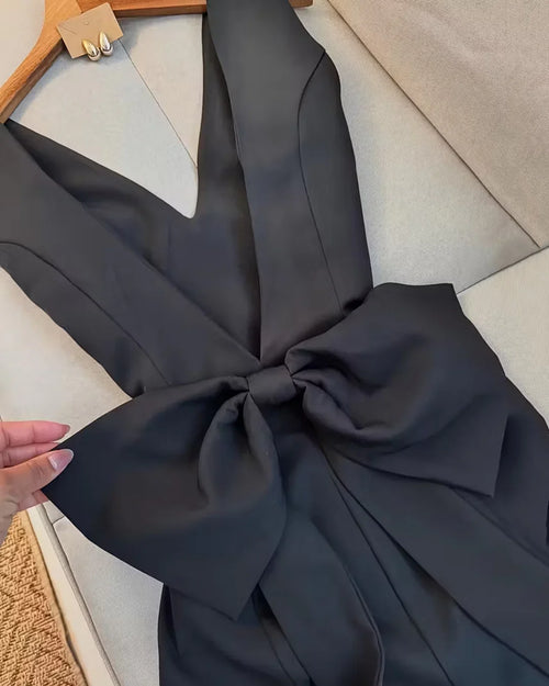 Close view of Black sleeveless V-neck mini dress with oversized bow detail, structured fit and sleek tailored silhouette