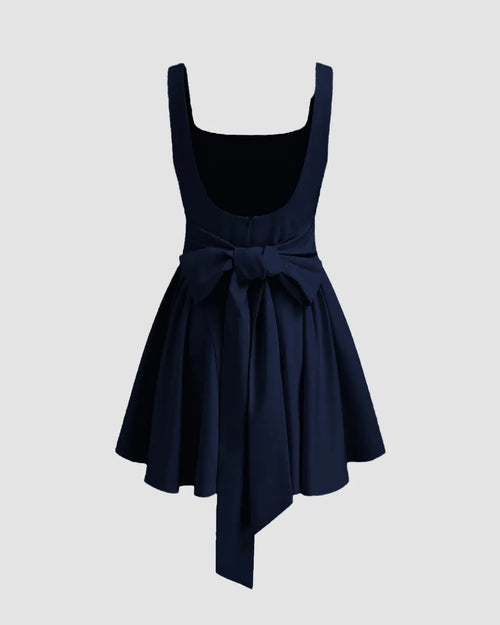 A navy blue mini dress featuring a square neckline, ruffle pleats, and a knotted detail for a structured, elegant silhouette.