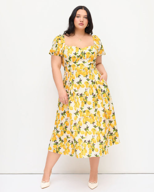 Women wearing plus size floral dress with lemon print, sweetheart neckline, puff sleeves and pleated midi silhouette.
