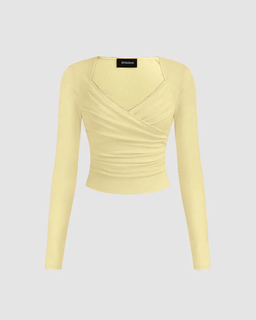 Front view of Solid ribbed vanilla knit cropped top with a V-neck and full sleeves, styled in a wrap design