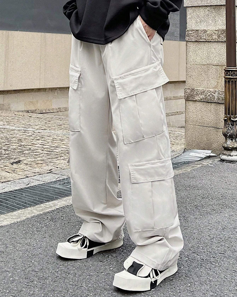 A man is standing on the street wearing white cargo pants.