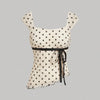 Front view of Asymmetric polka dot top with bow tie detail and ruched hem, fitted silhouette with playful print