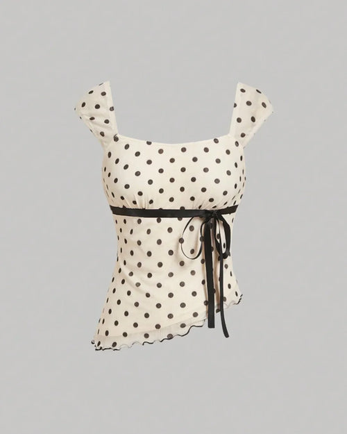 Front view of Asymmetric polka dot top with bow tie detail and ruched hem, fitted silhouette with playful print