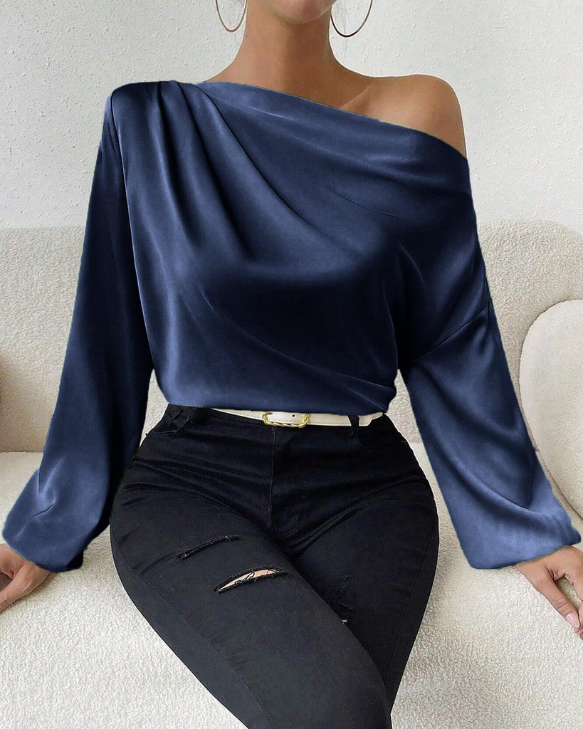 woman models a navy blue off-shoulder satin blouse with asymmetrical neck and lantern sleeves front view