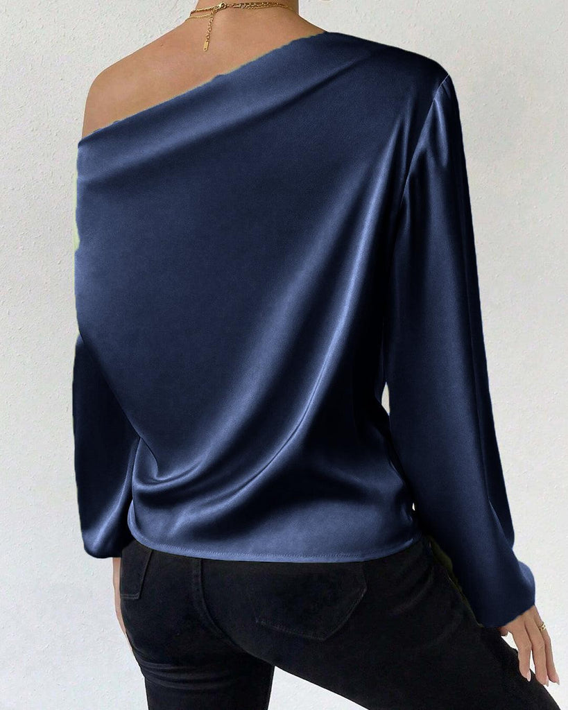 woman models a navy blue off-shoulder satin blouse with asymmetrical neck and lantern sleeves back view