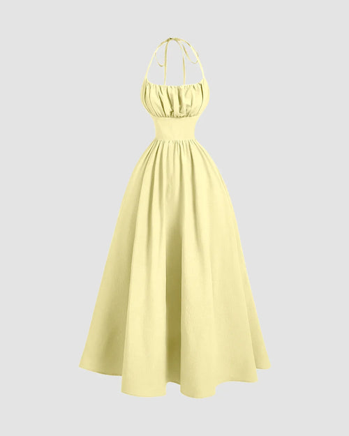 Front view of Halter neck midi dress in soft yellow with gathered bust, fitted waist, and flowy fit-and-flare skirt with tie-back detail.
