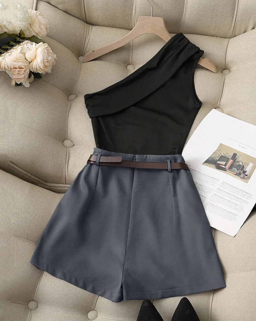 Black one-shoulder top paired with dark gray high-waist shorts, featuring a stylish belt for a coordinated look.
