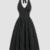 Black polka dot halter midi dress with deep V neckline, fitted waist, and full flared skirt, shown front and back.