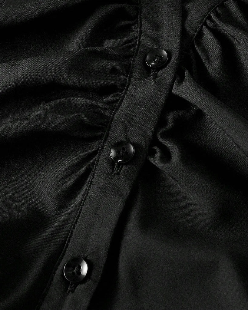 Close up of a chic blouse featuring a cinched waist, ruched bust, V-neckline, and a sharp collar, perfect for making a bold statement