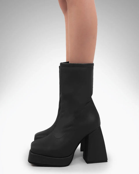 Women wearing Black slip-on platform ankle boots with chunky block heel and smooth finish, bold elevated sole design