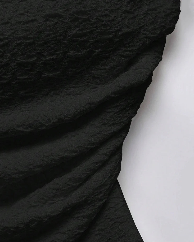 Close up of Ruched black tube top with an asymmetric hem, featuring a soft, textured design that flatters and adds a flirty touch