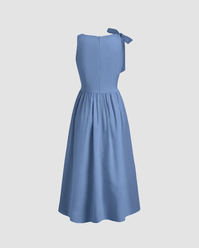 Back view of a fit and flare midi dress in French blue, showcasing a boat neck design and a decorative bow.