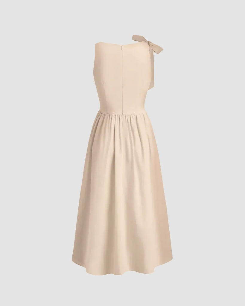 Fit and flare midi dress in light khaki with a clean boat neckline and dramatic bow tie shoulder, exuding soft elegance