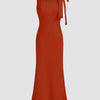  A brick red maxi dress featuring a boat neck and a decorative bow at the neckline.