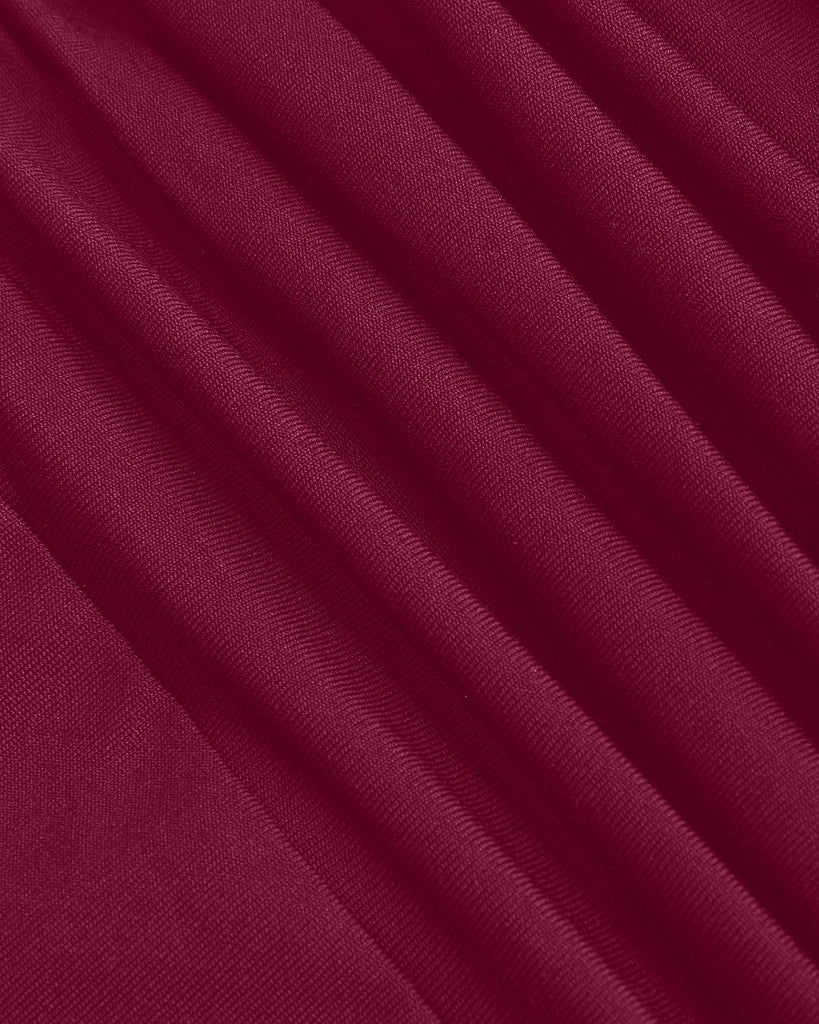 woman in a burgundy long-sleeve dress with an asymmetrical neck and black gloves close up view