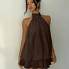 Front view of Brown layered mini dress with halter tie neck, flowy silhouette and soft drape, worn by a model against a plain studio wall