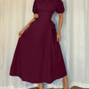 A woman models a burgundy puff sleeve A-line midi dress, showcasing its elegant design and rich color.
