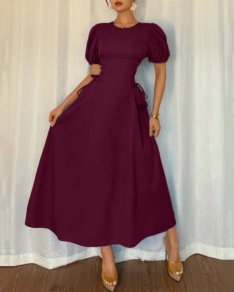 A woman models a burgundy puff sleeve A-line midi dress, showcasing its elegant design and rich color.
