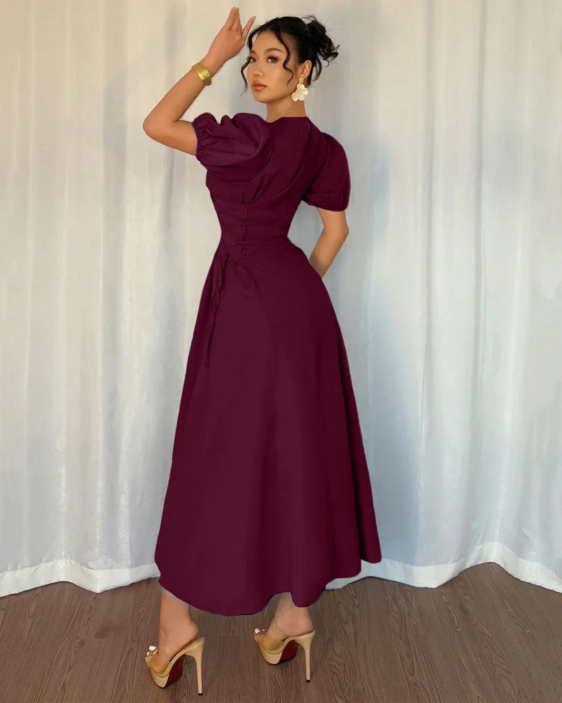 A woman models a burgundy puff sleeve A-line midi dress, showcasing its elegant design and rich color.
