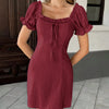 Burgundy mini dress featuring a square neckline, with front tie pleated details, and short puff sleeves