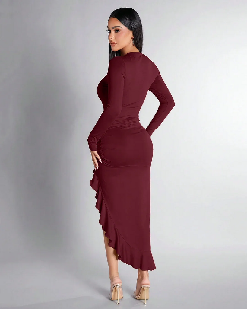 Back view of a Long-sleeved burgundy dress featuring a high slit and ruffle hem, elegantly ruched for a flattering silhouette.