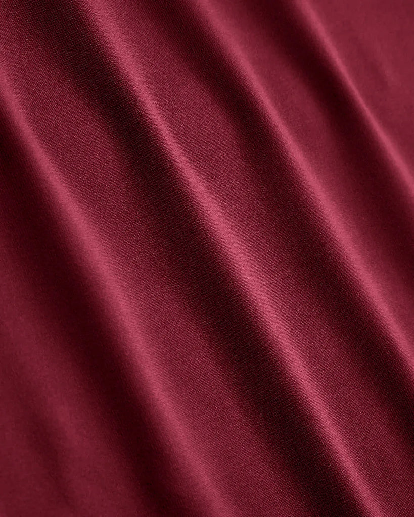 Close up of Burgundy slim fit top with a round neckline and subtle ruching at the waist, designed for comfort and a flattering silhouette