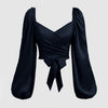 Front view of Black top featuring a front bow, solid color, and lantern sleeves with a braided tie back, pleated in navy blue.