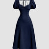 Front view of Navy blue fit-and-flare midi dress with puff sleeves, cinched waist and tie-back detail, shown from front and back.