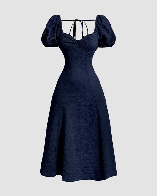 Front view of Navy blue fit-and-flare midi dress with puff sleeves, cinched waist and tie-back detail, shown from front and back.