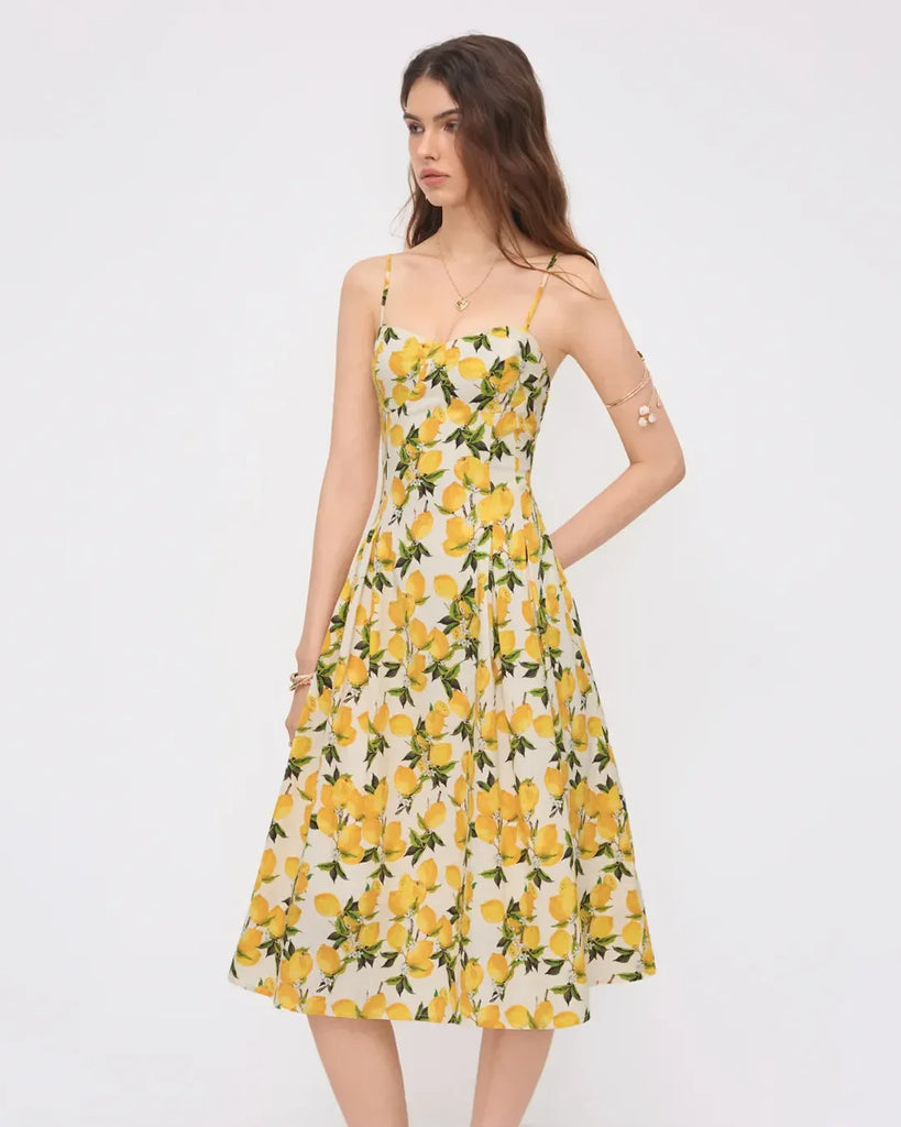 A strappy fit and flare midi dress featuring a vibrant lemon print, titled Citrus Bloom.
