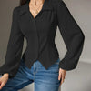 A woman in a black collared long sleeve shirt and jeans poses, showcasing a stylish and casual look.