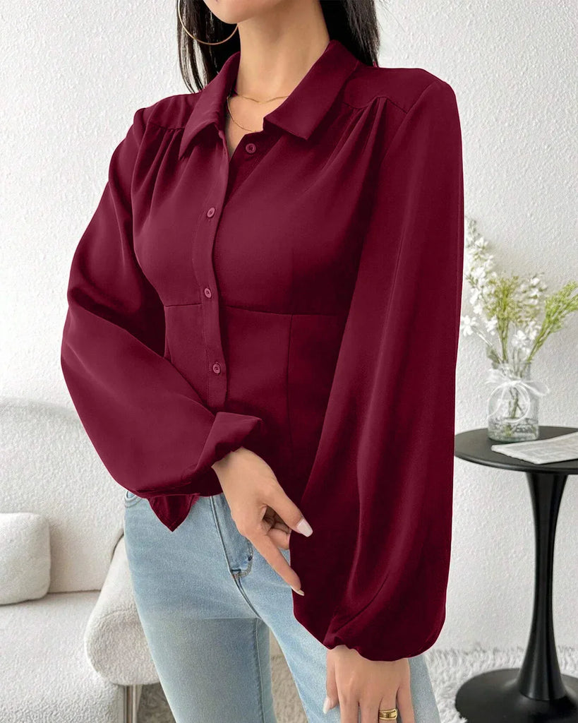 A woman wearing a fitted long sleeve collared button-down shirt in raspberry color.