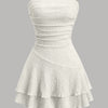 Front view of bandeau dress in off white with textured fabric, ruched bodice and layered ruffle hem, flared mini style