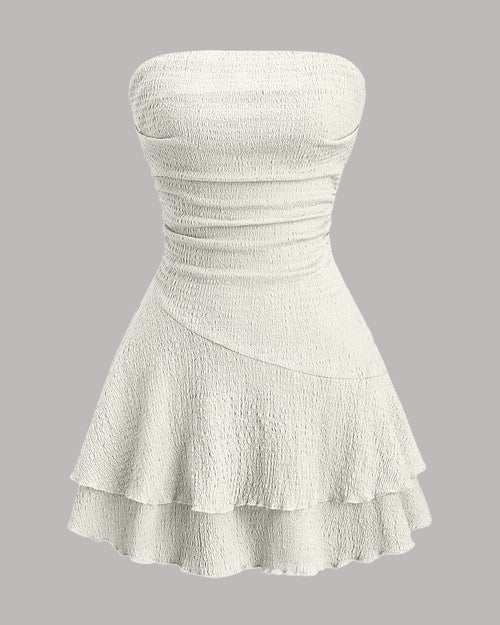 Front view of bandeau dress in off white with textured fabric, ruched bodice and layered ruffle hem, flared mini style