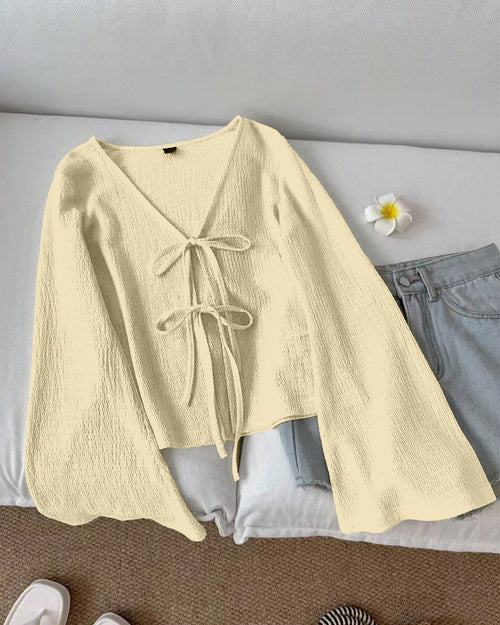 Front view of beige top women with tie front detail, long sleeves and textured fabric for a relaxed stylish look.
