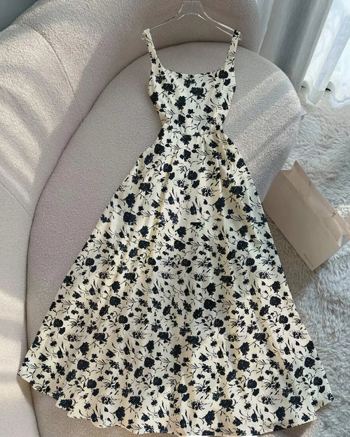 Front view of Sleeveless floral dress in ditsy print with a fit and flare silhouette, thin straps, laid flat on a neutral-toned sofa