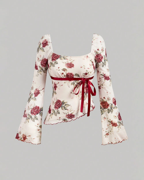 Front view of floral bell sleeve crop top with a square neckline, bow tie detail, and asymmetrical hem, featuring a fitted and feminine silhouette