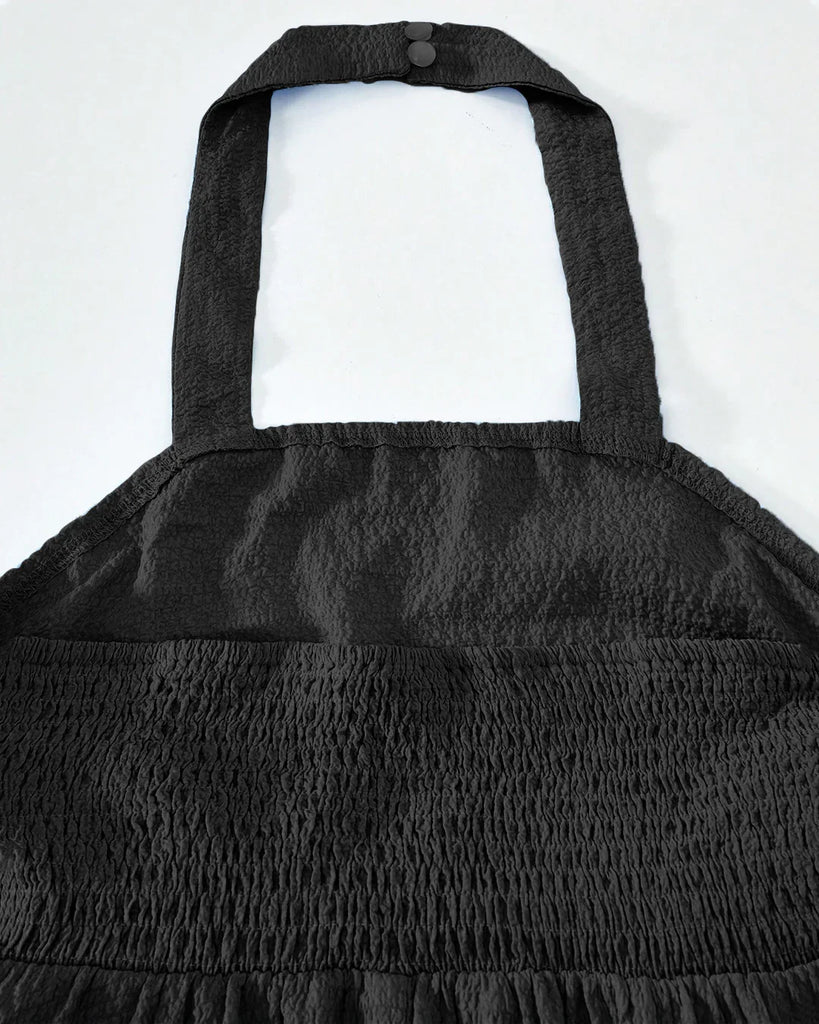 Closed view of a Black halter neck mini dress with a ruched waist and a tiered ruffled skirt, perfect for a stylish evening out.