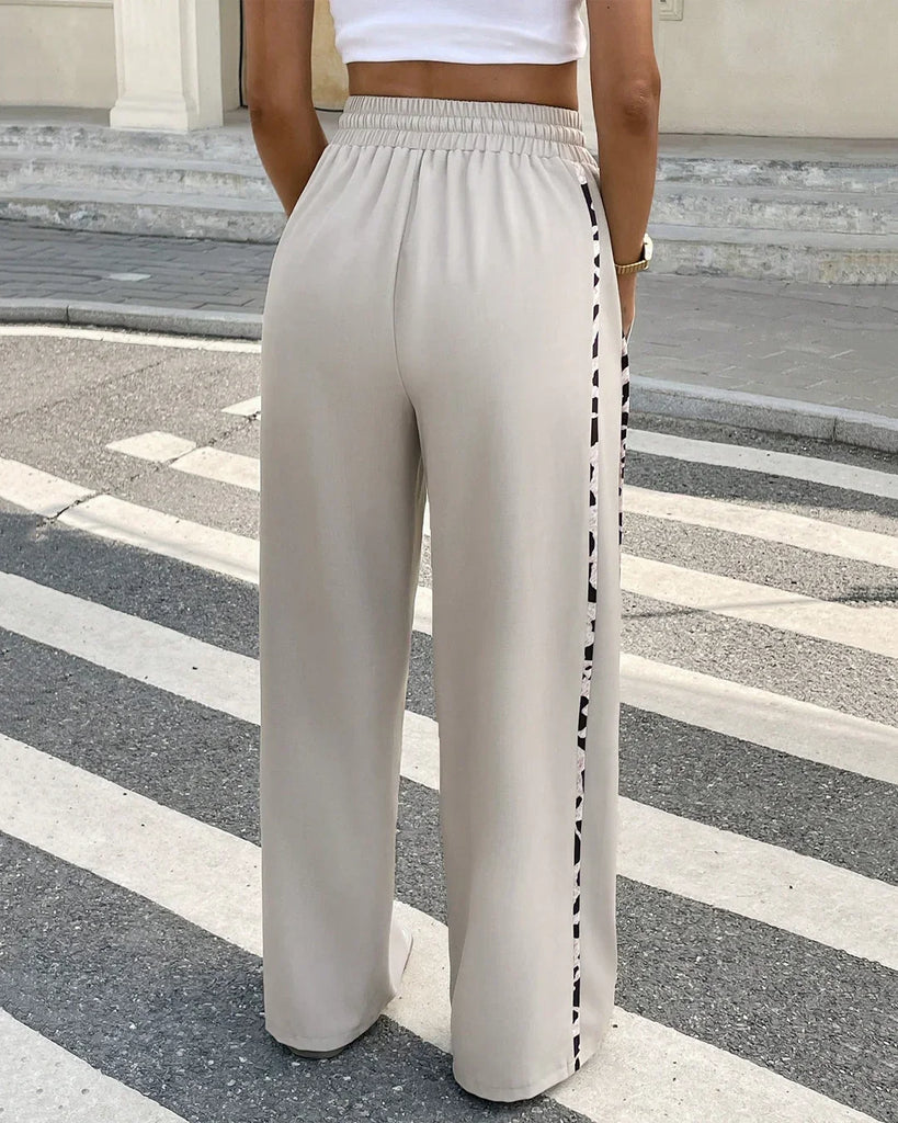 Back view of a high-rise wide-legged trousers with side tape details, posing confidently.