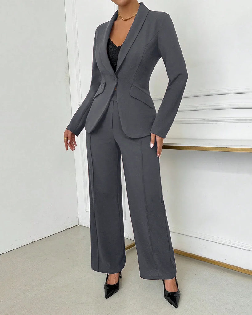 A woman wearing a fitted dark grey blazer and high-waisted trousers, complemented by stylish heels.
