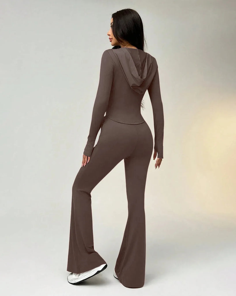 Back view of a woman in a brown sporty suit with a zippered hoodie takes a selfie, smiling at the camera.