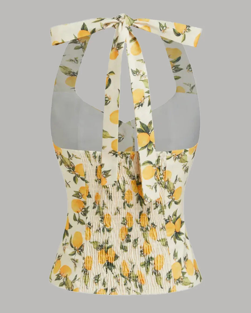 Back view of a White and yellow lemon print halter neck top with a ruched design and a stylish bow detail.
