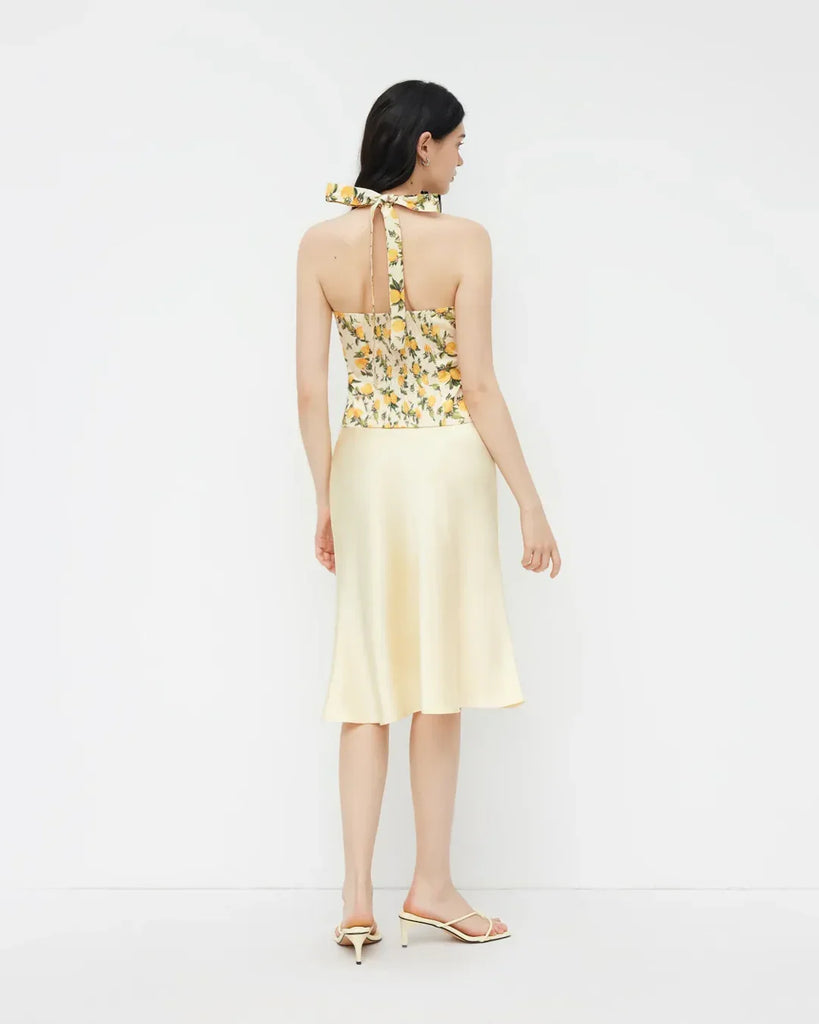 Back view of a White and yellow lemon print halter neck top with a ruched design and a stylish bow detail.