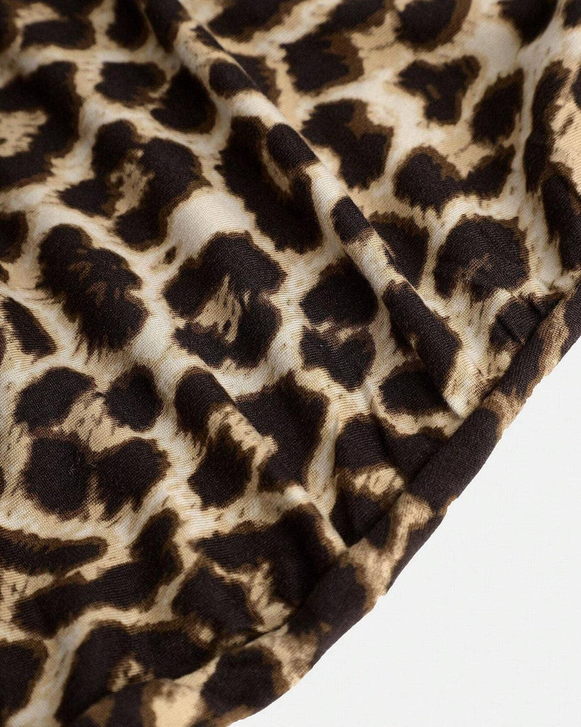Close Up of A bodycon dress featuring a leopard print design, asymmetrical shoulder, and ruched waist made from stretchy fabric.