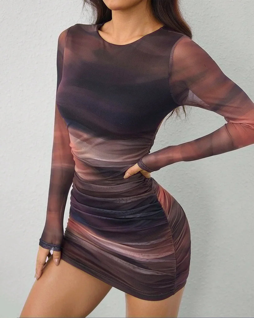 A woman poses for the camera in a long sleeve mesh print ruched bodycon mini dress and stylish boots.