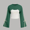 Front view of Green crop top sweatshirt with cut-out front, flared long sleeves and tie-up details, layered over a white fitted inner top